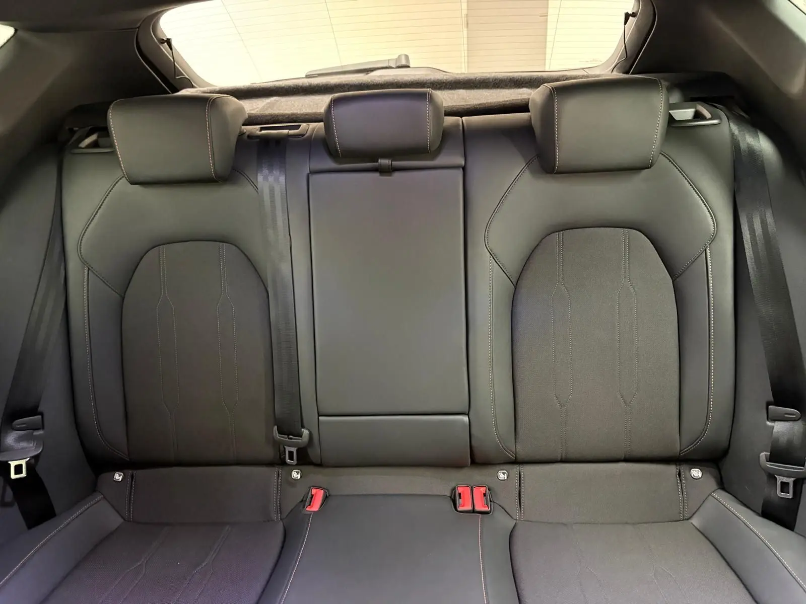 Vue intérieure sur la banquette arrière en cuir noir du CUPRA Leon Phase 2 2025, avec appuie-têtes et ceintures visibles.