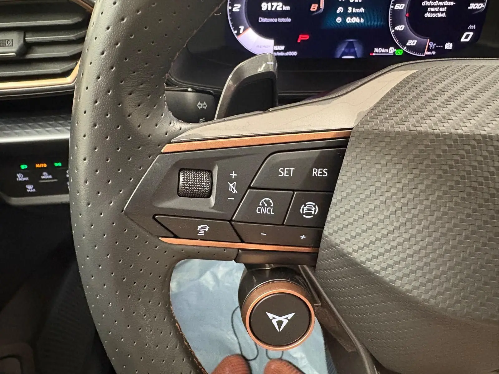 Gros plan sur le volant côté gauche du CUPRA Leon 2025 avec commandes intégrées et finition carbone.