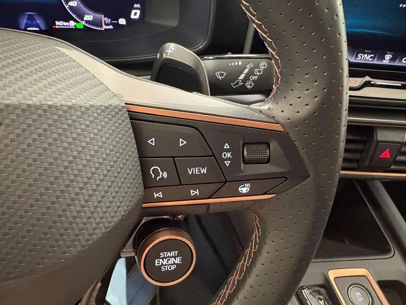 Gros plan sur le volant perforé de la CUPRA Leon blanc Nevada avec commandes multifonctions et bouton start engine stop.