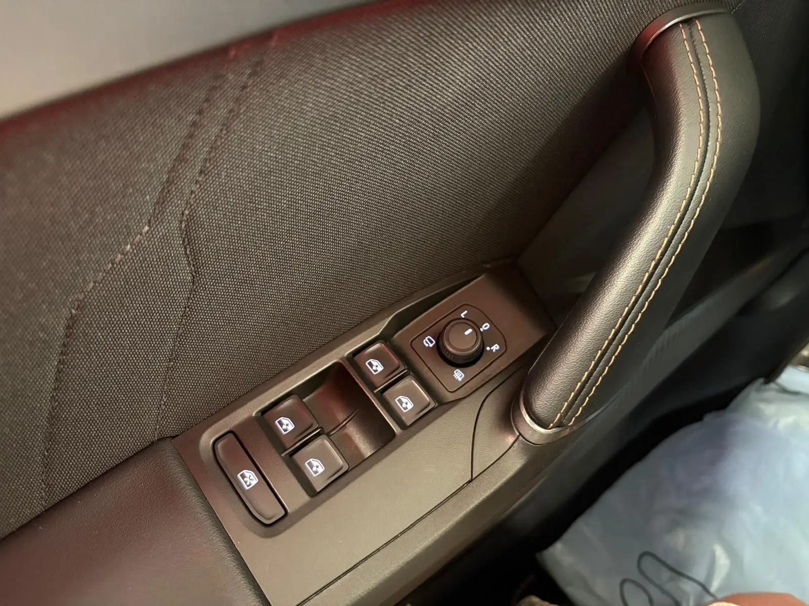 Gros plan sur la commande des vitres et rétroviseurs côté conducteur de la CUPRA Leon blanc Nevada.