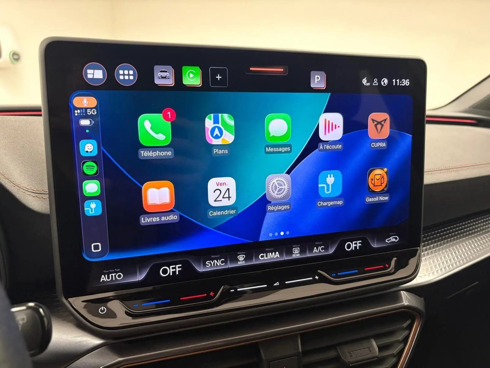 Écran tactile central de la CUPRA Leon blanc Nevada 2025 affichant des applications connectées et commandes climatisation.