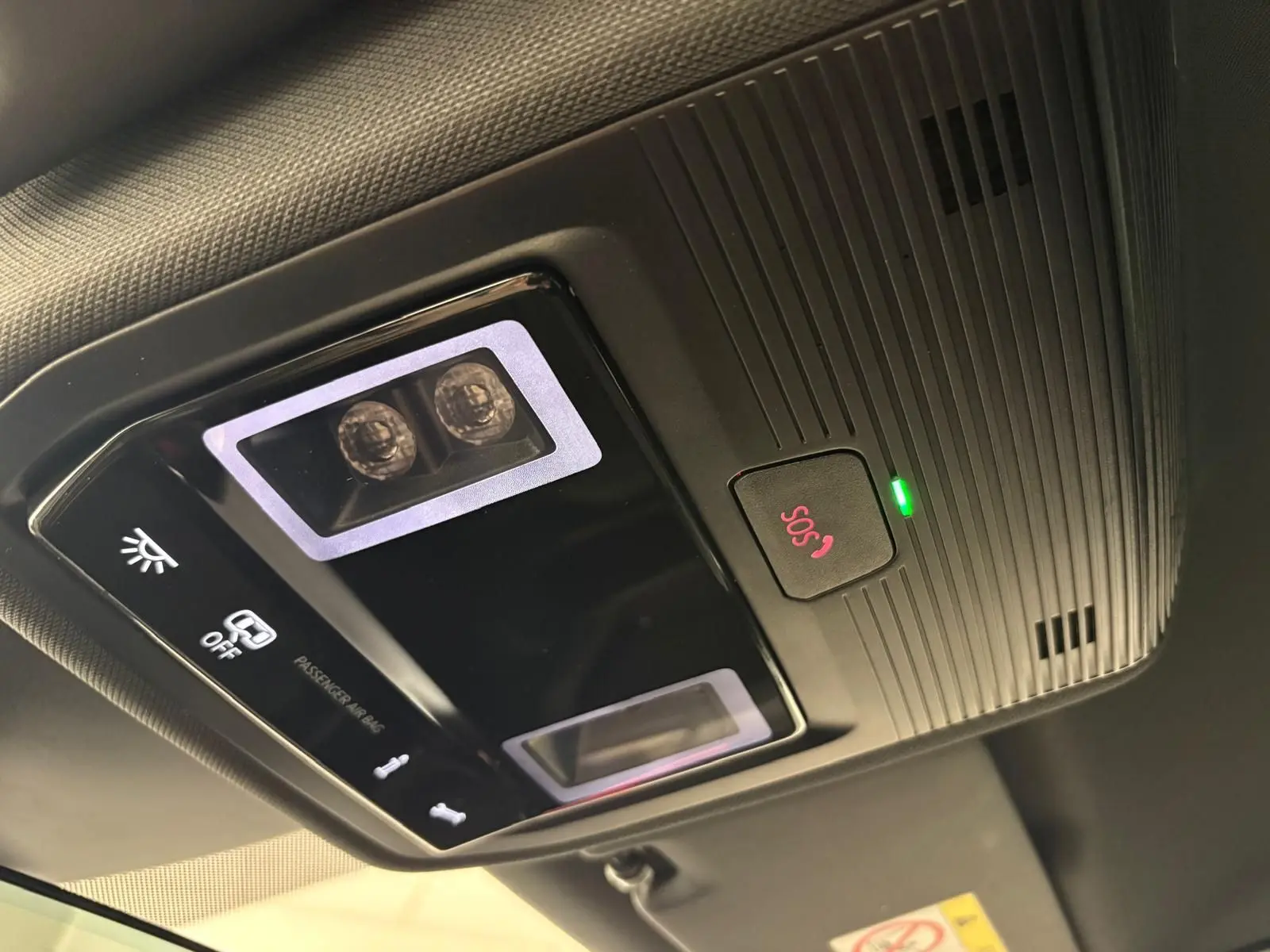 Vue en gros plan du plafonnier intérieur noir avec bouton SOS rouge et éclairage LED du CUPRA Leon Blanc Nevada 2025.