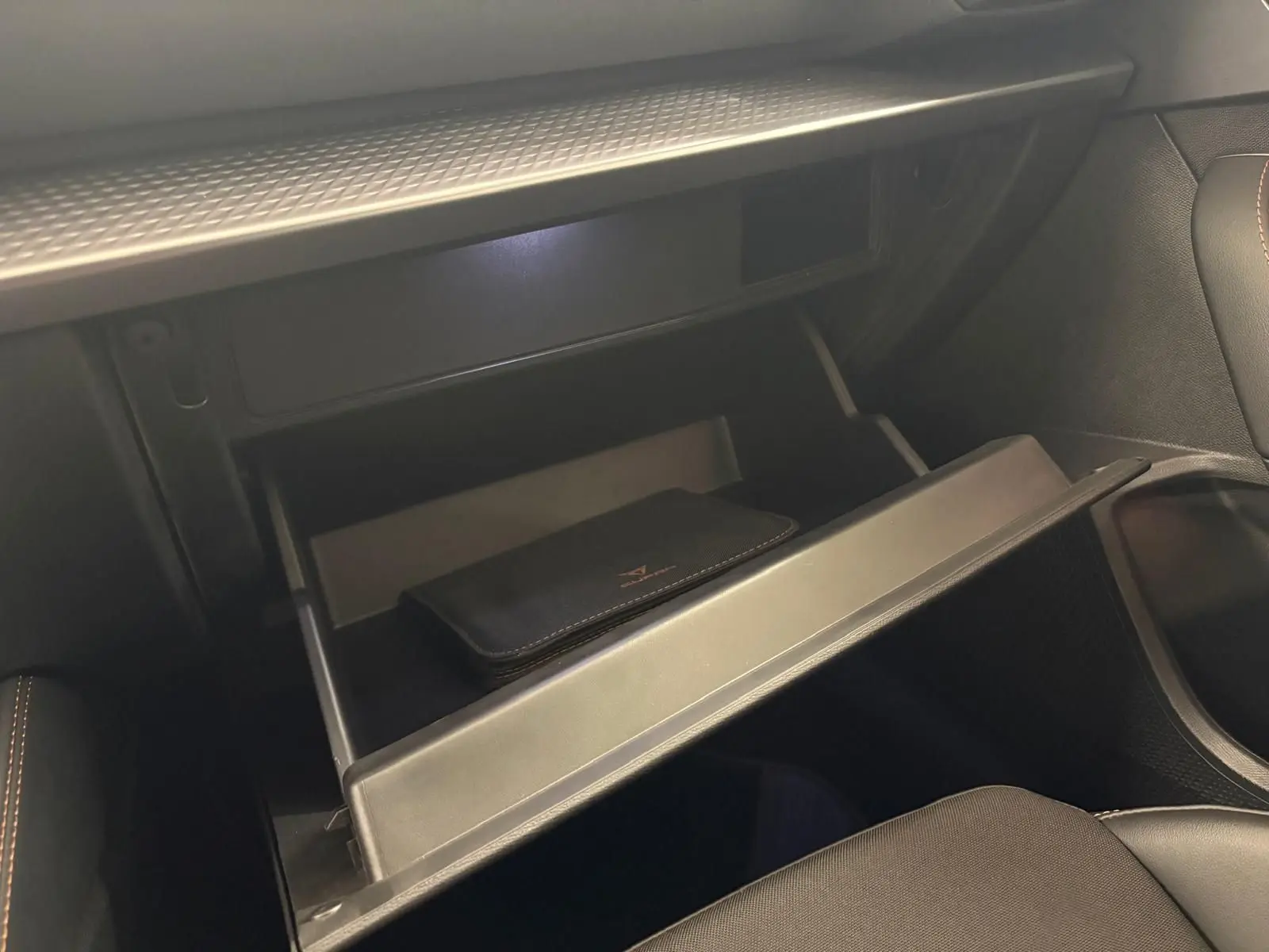 Gant de boîte à gants ouvert avec pochette noire, intérieur avant droit de la CUPRA Leon Phase 2 Blanc Nevada 2025.