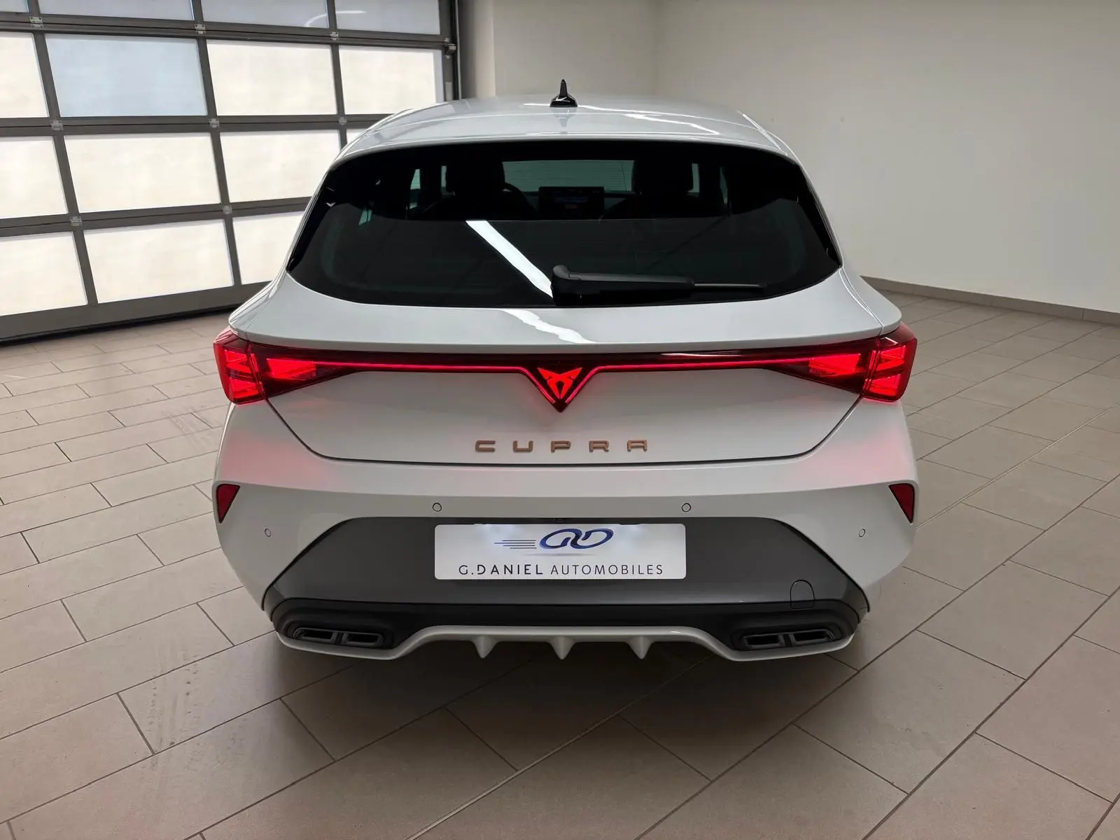 Vue arrière d'une CUPRA Leon Phase 2 blanche Nevada avec feux LED reliés et double sortie d'échappement intégrée.