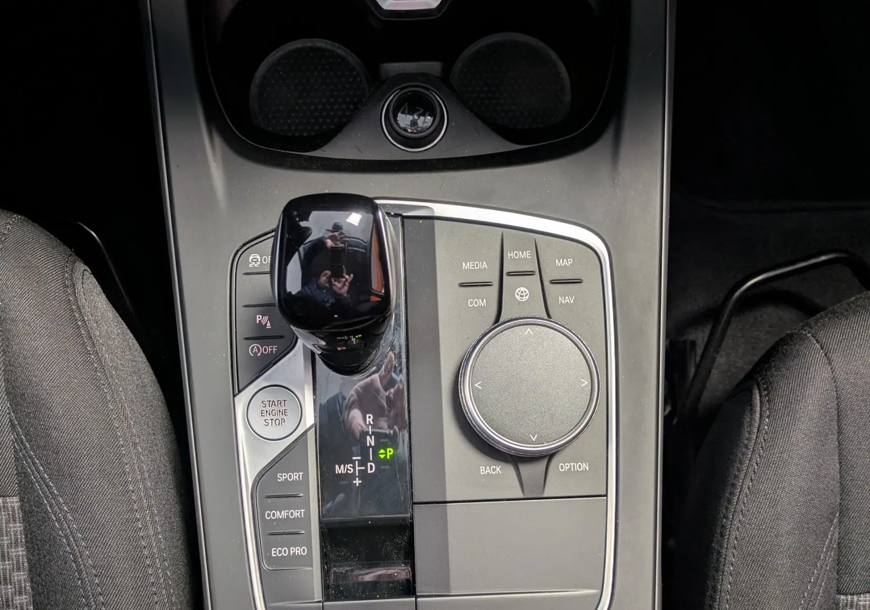 Vue plongeante sur la console centrale noire de la BMW Série 1 116d 2022 avec levier de vitesses et commandes multimédia.