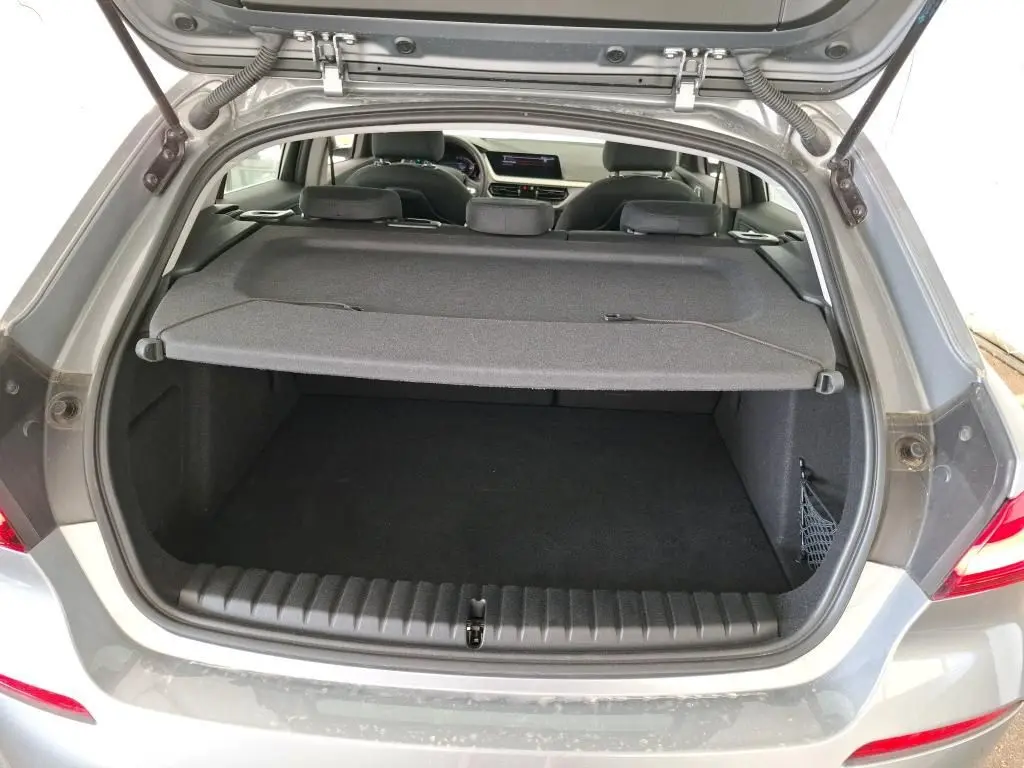 BMW Série 1 gris vue 3/4 arrière droit, jantes alliage, feux arrière LED, stationnement en intérieur showroom.