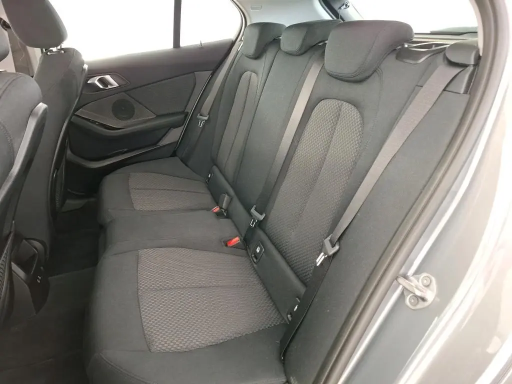 Gros plan sur les commandes de lève-vitres et réglage des rétroviseurs côté conducteur d'une BMW Série 1 gris 2022.