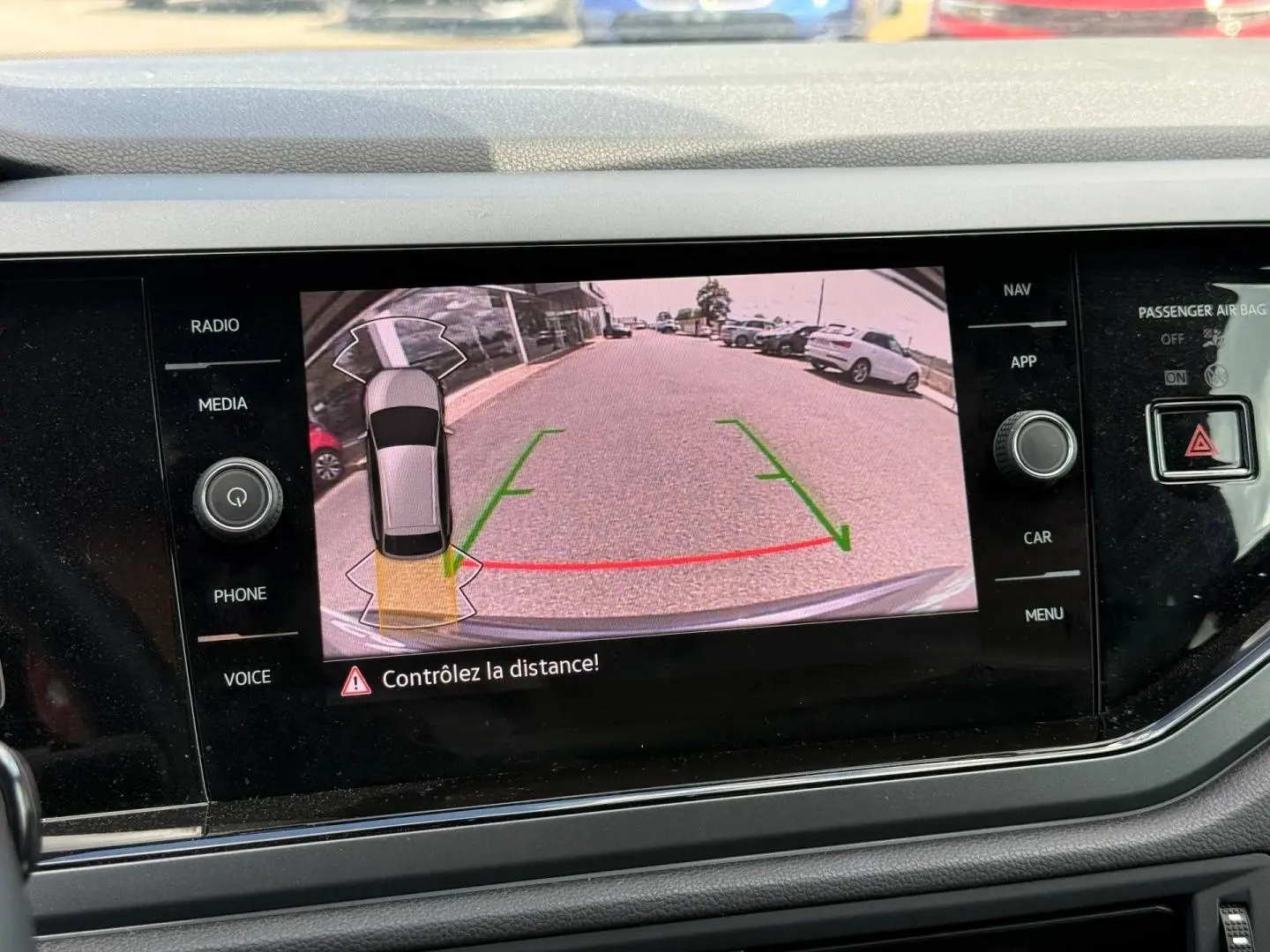 Écran tactile intérieur montrant la caméra de recul avec vue arrière et guidage vert et rouge du Volkswagen Taigo gris.