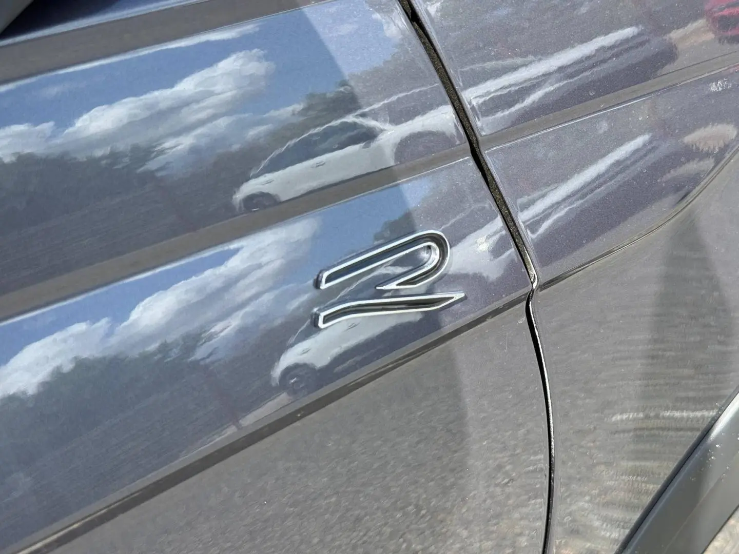 Gros plan sur l'aile avant droite gris Ascot du Volkswagen Taigo 1.0 TSI 116ch R-Line avec logo "R" chromé.