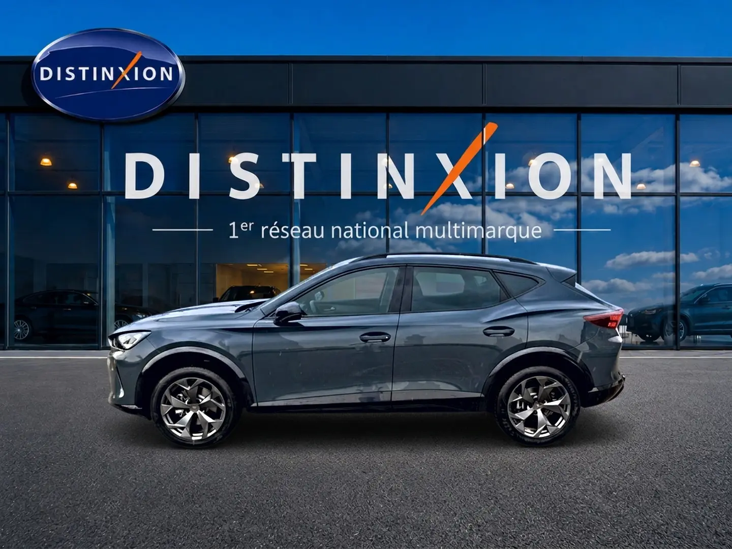 Vue de profil côté gauche d'une CUPRA Formentor 1.5 etsi hybrid 2026 en bleu fjord devant une vitrine Distinxion.