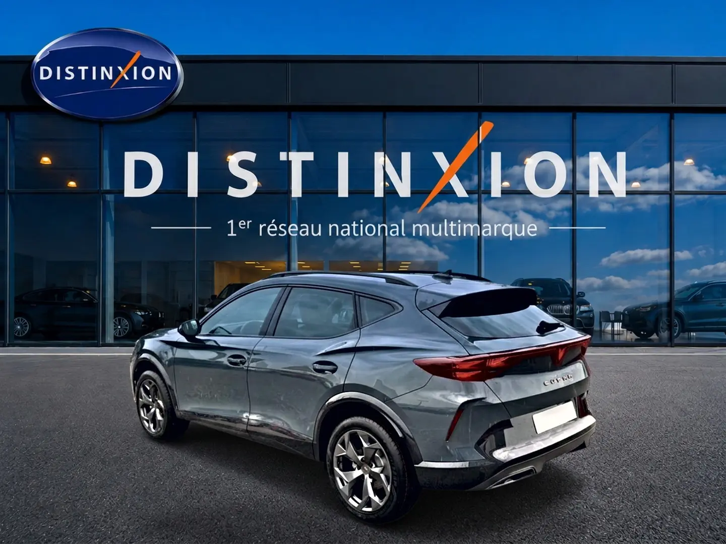 Vue 3/4 arrière droite d'un CUPRA Formentor bleu fjord avec feux arrière LED et jantes alliage devant un showroom Distinxion.