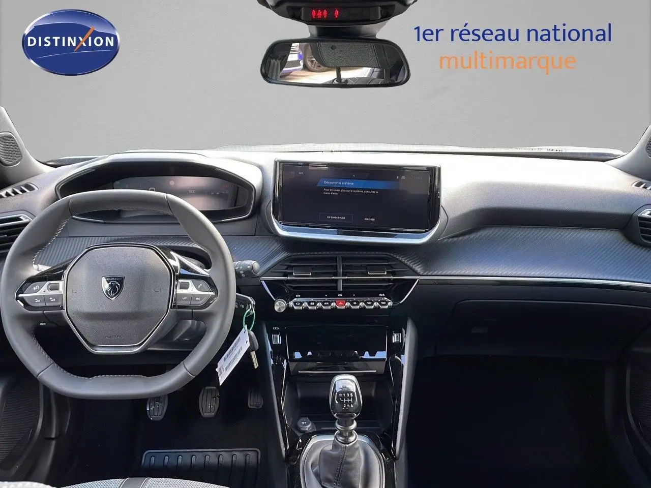 Vue intérieure avant du Peugeot 2008 gris Artense, mettant en valeur le tableau de bord et la boîte manuelle.