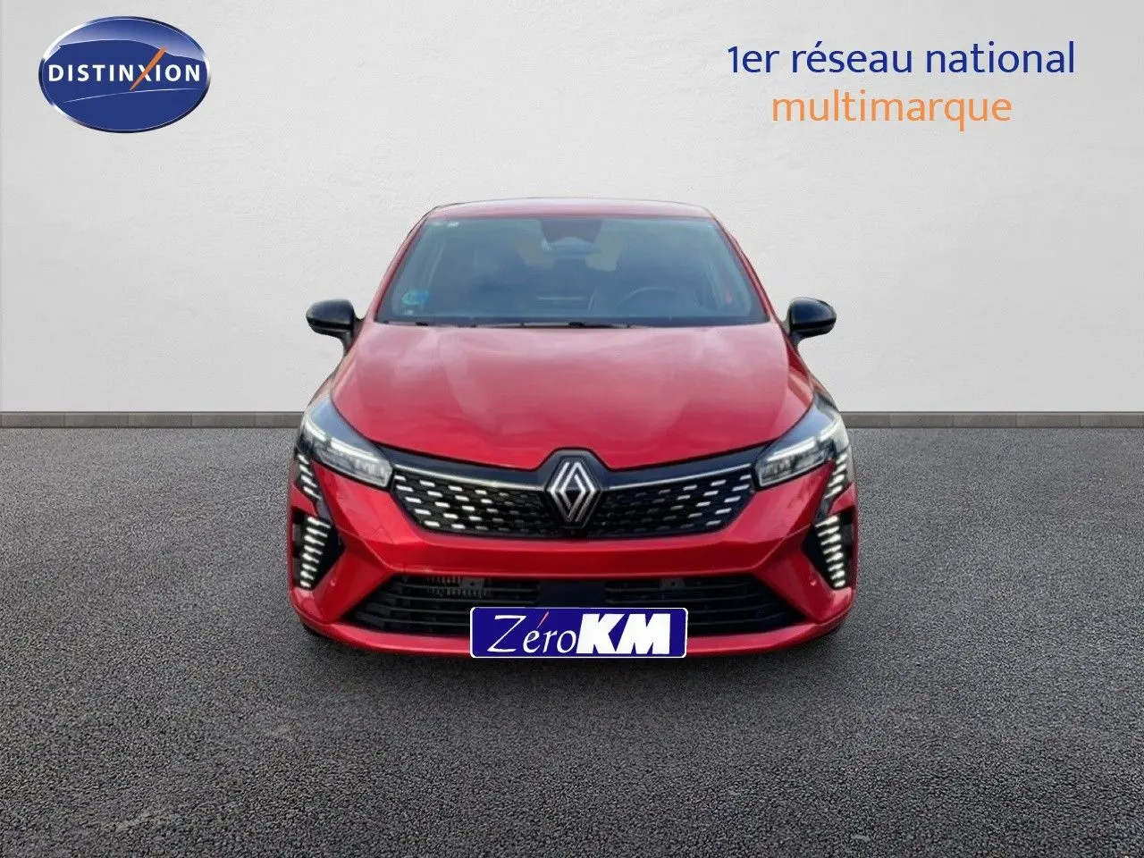 Vue frontale d'une Renault Clio 2025 rouge désir métal avec calandre noire et phares LED allumés.