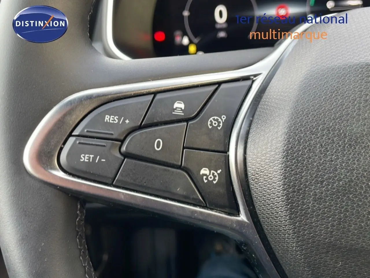 Gros plan sur les commandes au volant de la Renault Clio 2025, boutons noirs avec cadre argenté sur cuir noir.