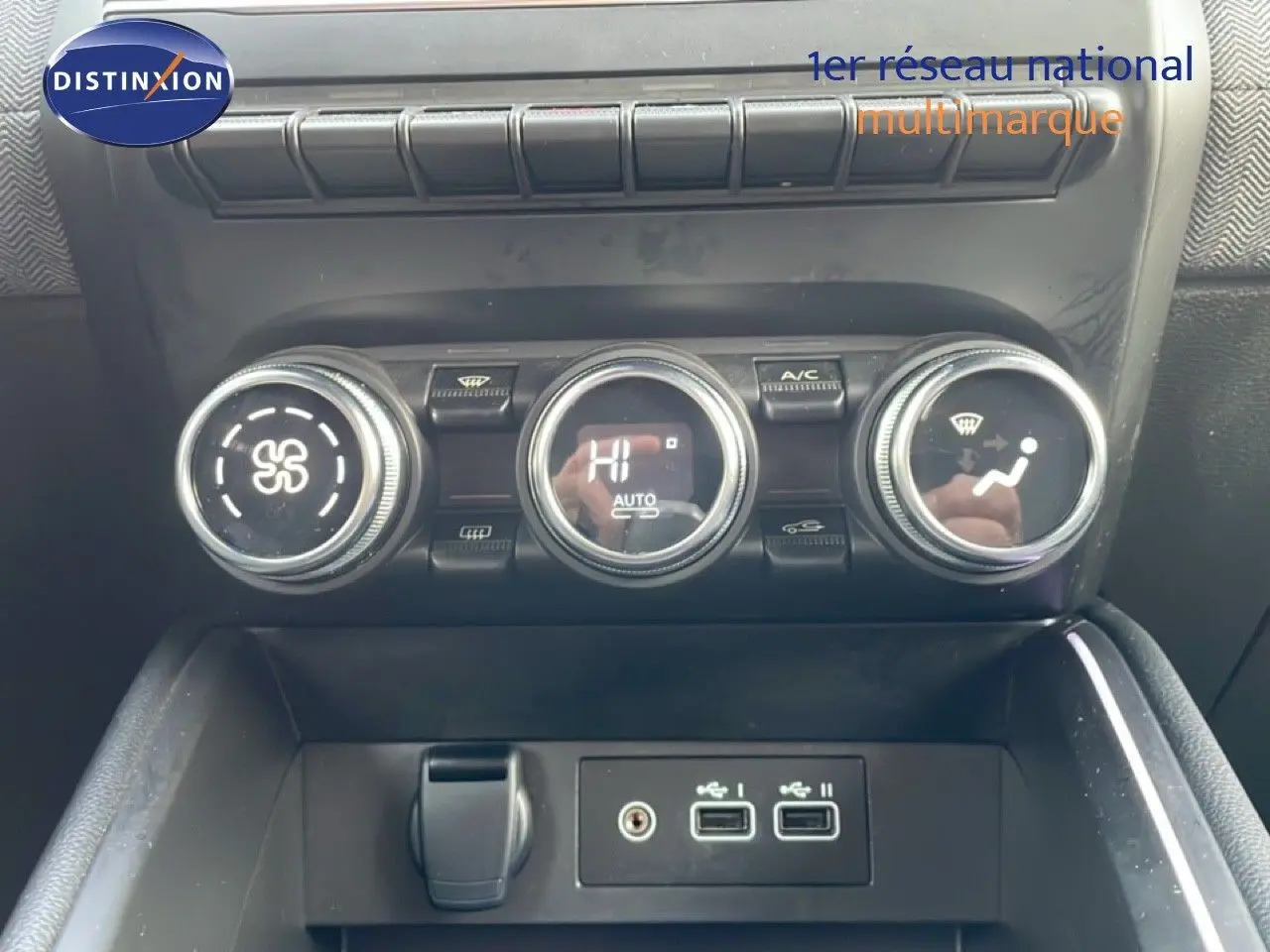 Vue rapprochée de la console centrale de la Renault Clio rouge, montrant les commandes de climatisation et ports USB.