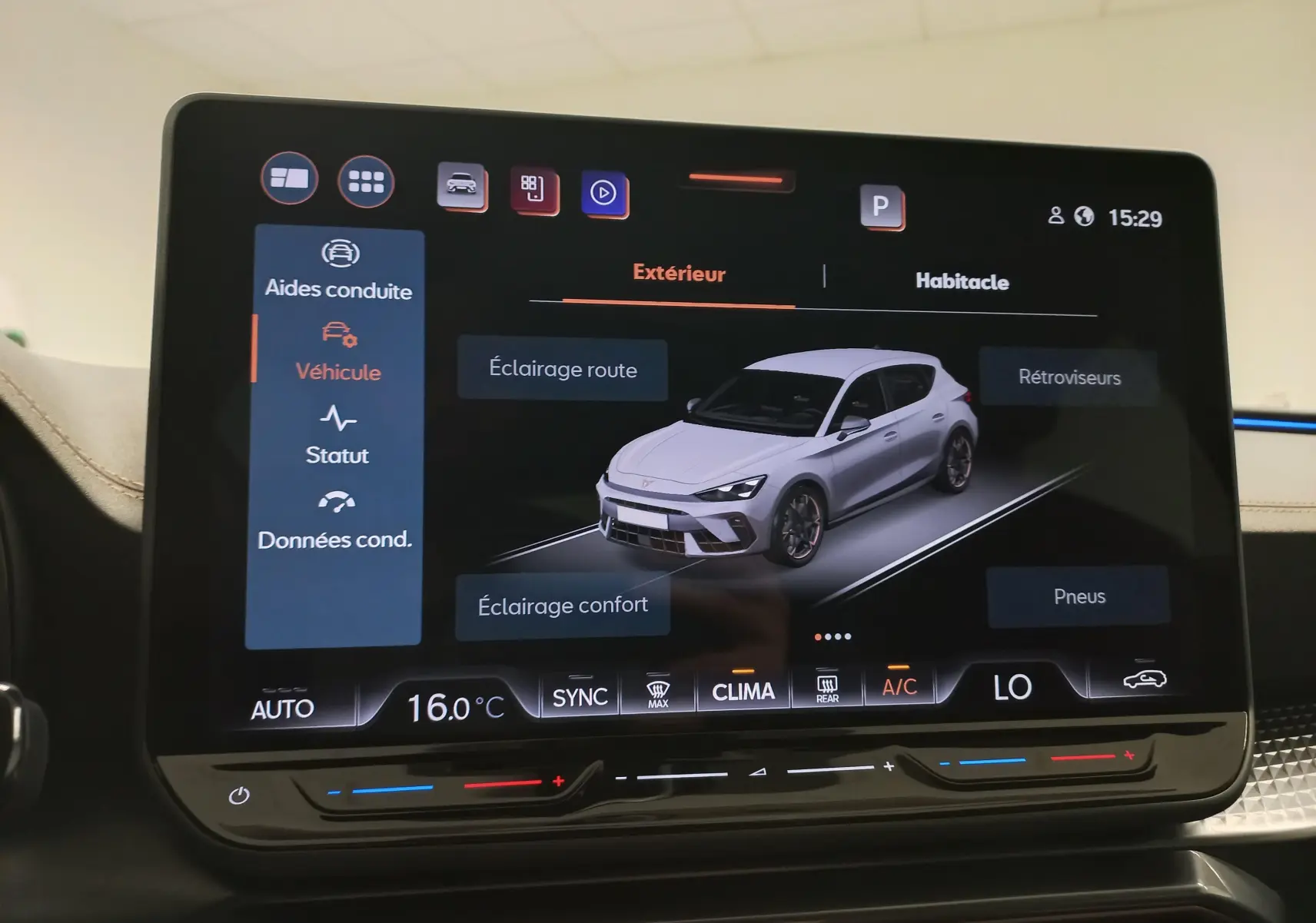 Écran tactile intérieur montrant une vue 3/4 avant d'une CUPRA Leon blanche Nevada sur l'interface du véhicule.