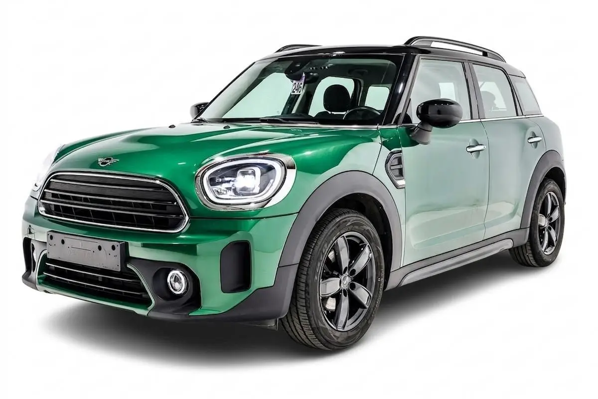 Vue 3/4 avant gauche d'une MINI Countryman vert métallisé avec toit noir et jantes noires.