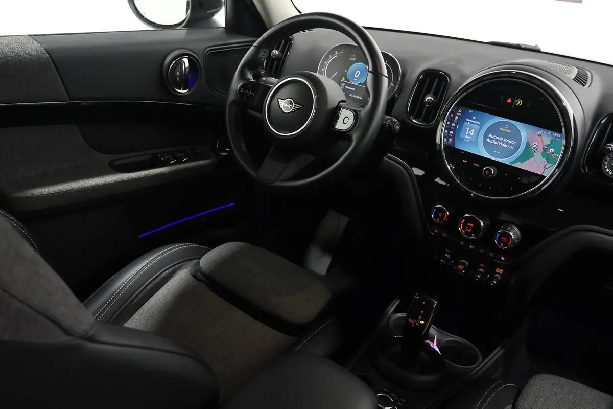 Vue intérieure côté conducteur de la MINI Countryman 136 BVA, tableau de bord avec écran tactile et éclairage d'ambiance bleu.