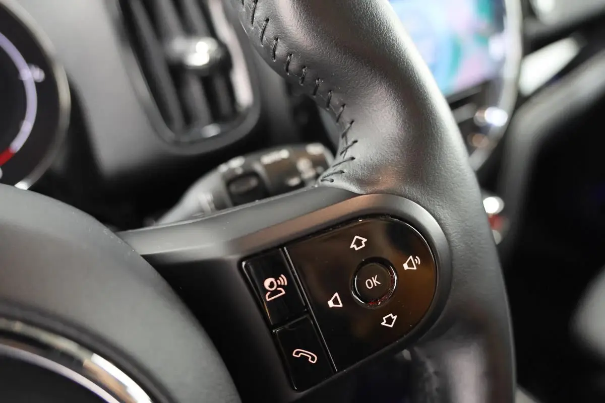 Gros plan sur les commandes du volant en cuir noir du MINI Countryman 2021, avec boutons de navigation et téléphone.