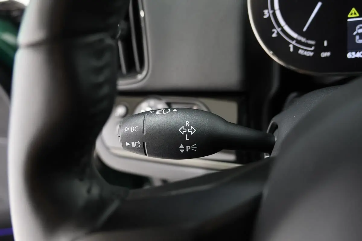 Gros plan sur la commande de clignotant à gauche du volant dans l'habitacle d'une MINI Countryman vert métallisé.