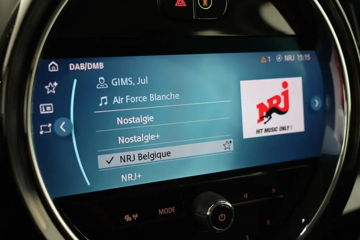 Écran central de la MINI Countryman 2021 affichant la radio NRJ Belgique avec interface moderne et cercle lumineux chromé.
