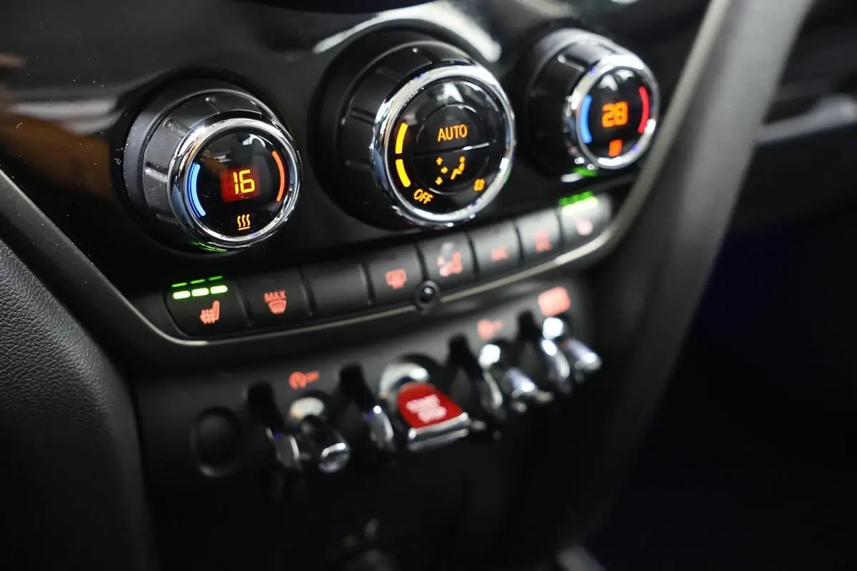 Gros plan sur la console centrale du MINI Countryman 2021, montrant les commandes de climatisation et les interrupteurs chromés.