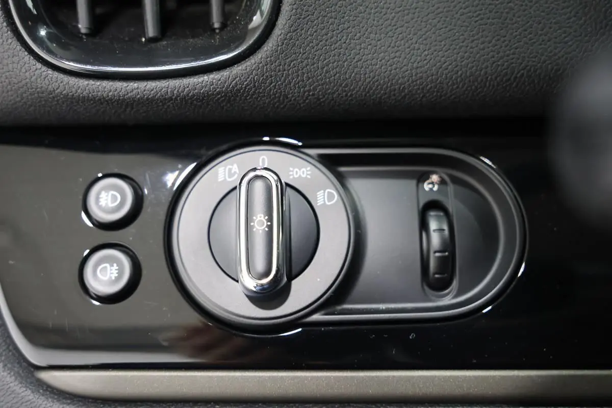 Gros plan sur la commande des phares et réglage des feux d’un MINI Countryman 2021, finition noire brillante.