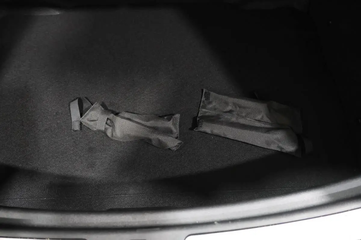 Coffre ouvert d’une MINI Countryman vert métallisé, montrant un intérieur noir avec deux sangles textiles.