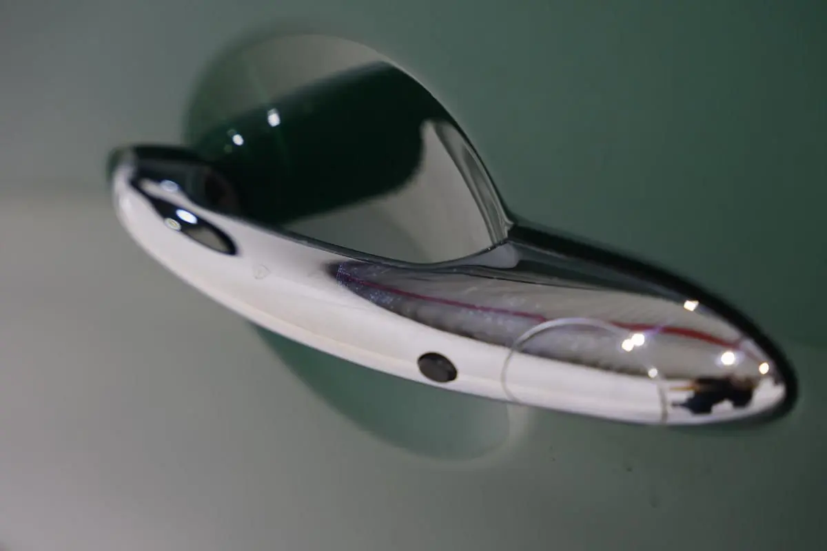 Poignée de porte chromée en gros plan sur une MINI Countryman vert métallisé, côté droit du véhicule.