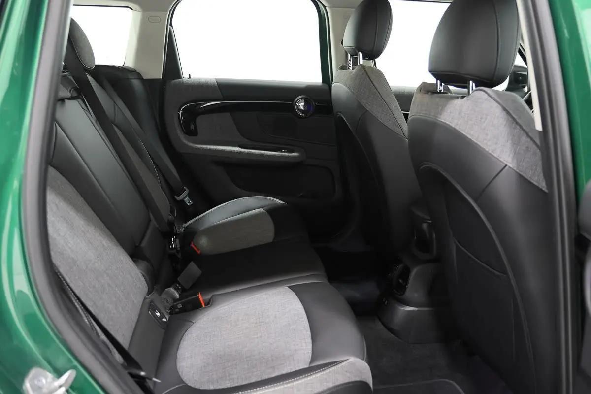 Vue intérieure arrière côté gauche d'un MINI Countryman vert métallique, sièges bicolores tissu et cuir gris et noir.