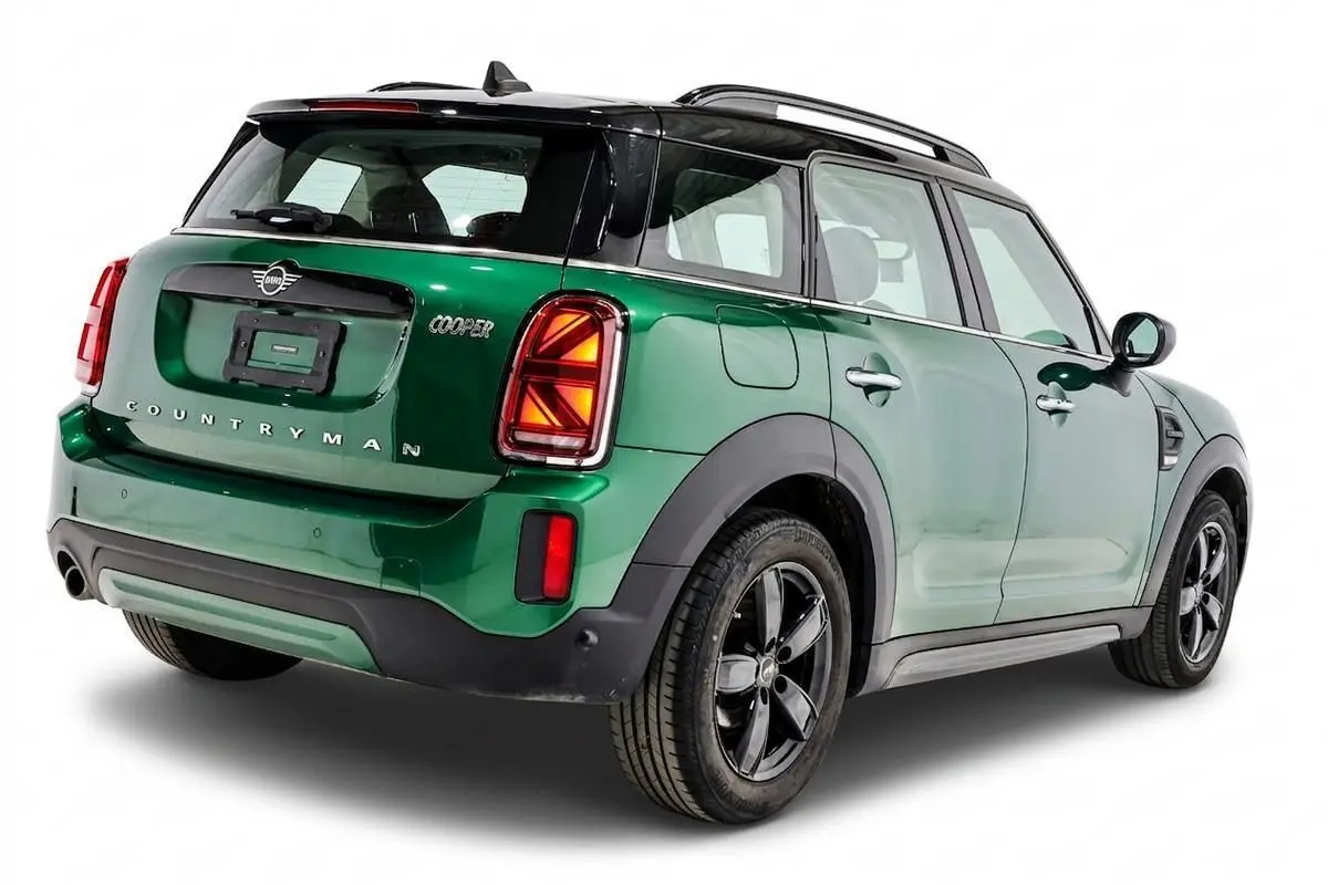 Vue 3/4 arrière droite d'un MINI Countryman vert métallisé avec toit noir et jantes noires.