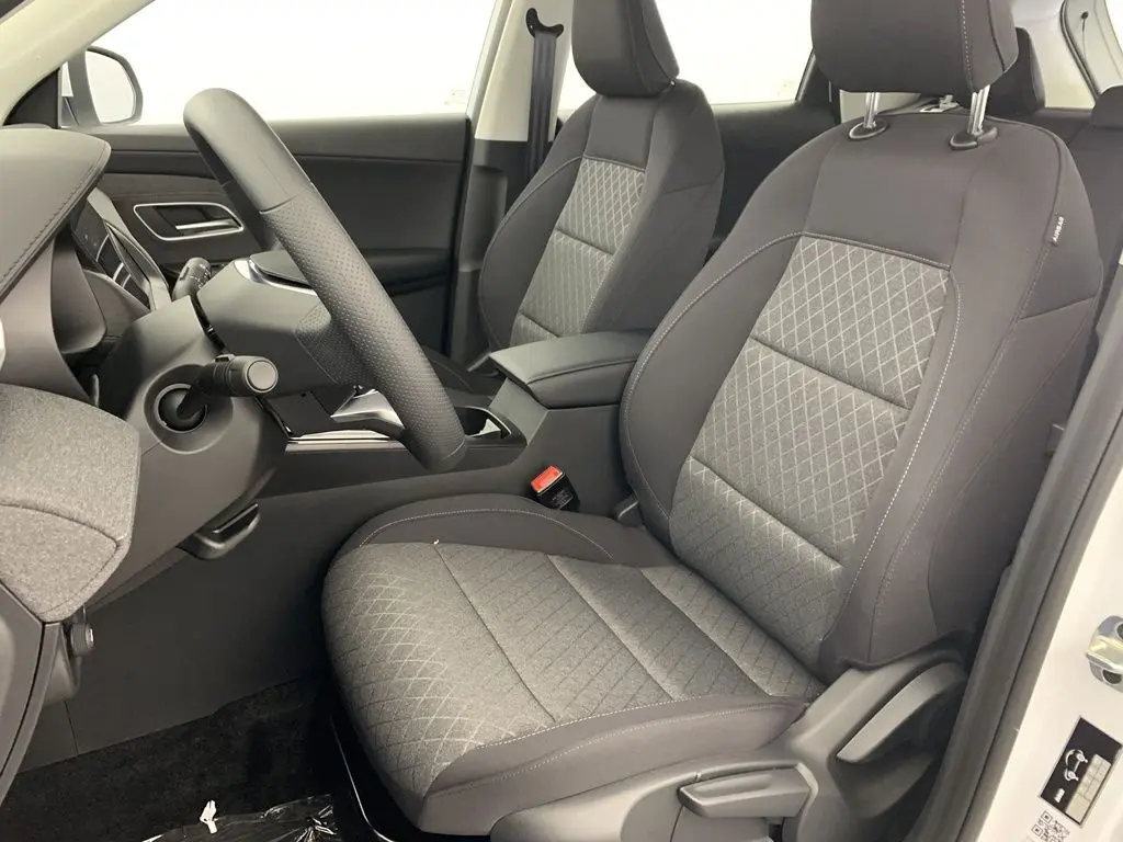 Vue intérieure côté conducteur du MG ZS 2026, sièges tissu gris à motifs losanges et volant multifonction noir.
