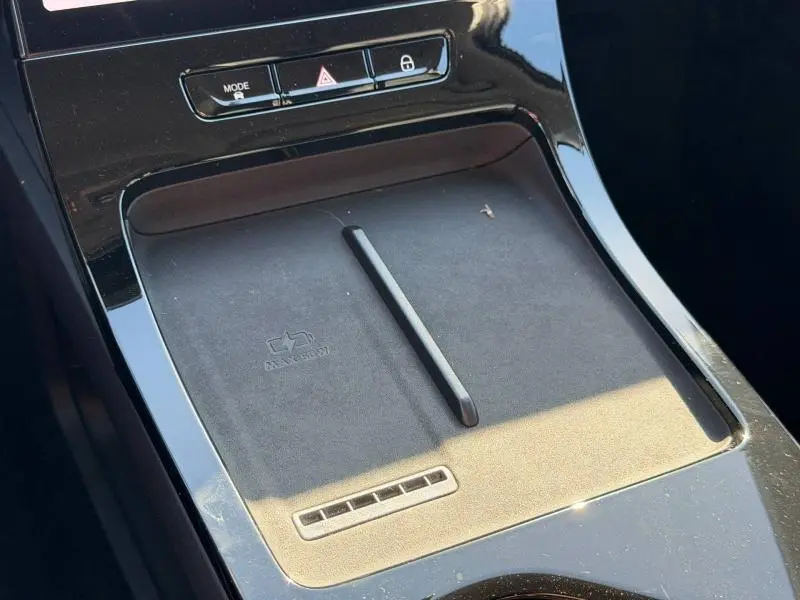 Vue rapprochée de la console centrale noire brillante du JAECOO J5 avec surface de charge sans fil et boutons de contrôle.