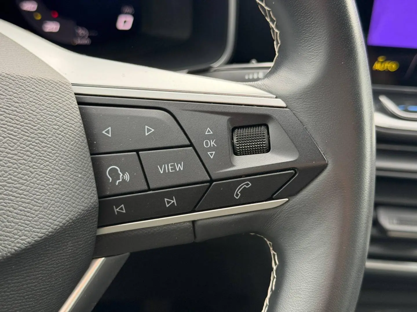 Gros plan sur les commandes multifonctions en cuir noir du volant de la SEAT LEON 2.0 TDI 2025.
