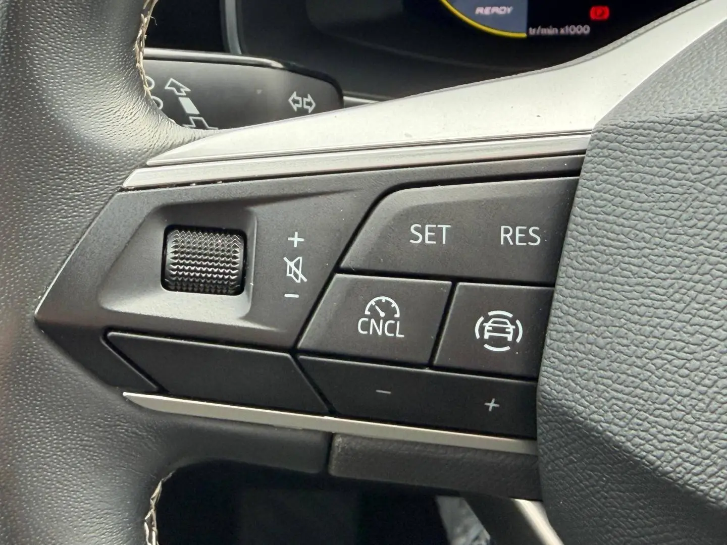 Gros plan sur les commandes du volant cuir multifonction du SEAT LEON gris Magnétique, boutons de régulateur de vitesse visibles.
