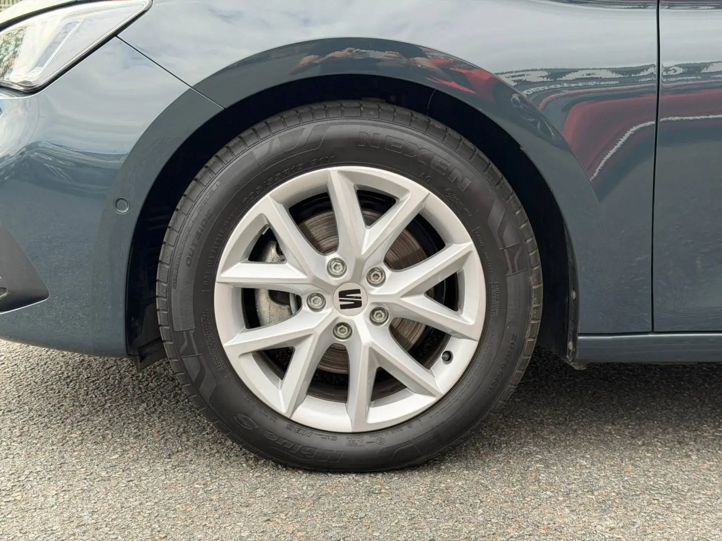 Gros plan sur la roue avant gauche et la jante alu grise d'une SEAT LEON gris magnétique métallisée.