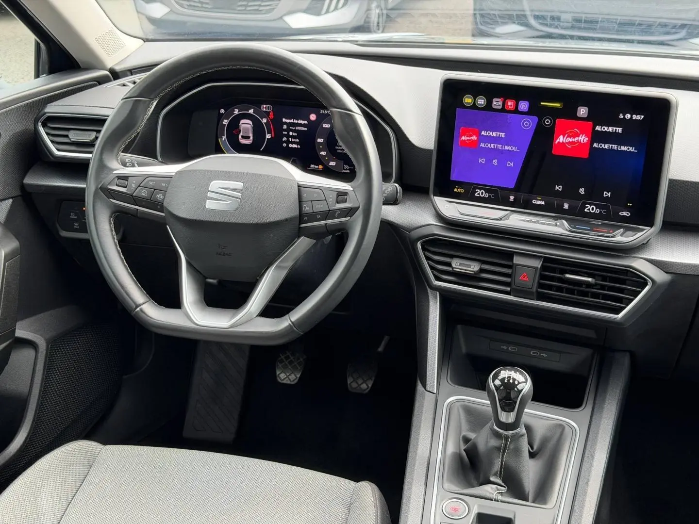 Vue intérieure du poste de conduite SEAT Leon 2025, volant cuir multifonction et écran tactile central lumineux.