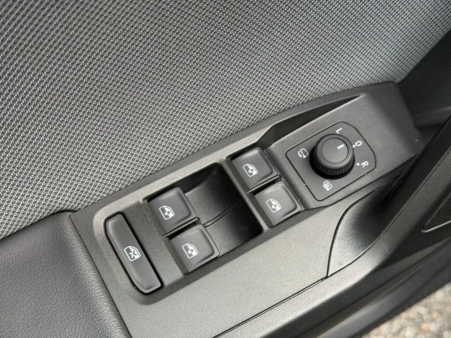 Détail des commandes de lève-vitres et réglage des rétroviseurs sur la portière côté conducteur d'une SEAT Leon gris métallisé.