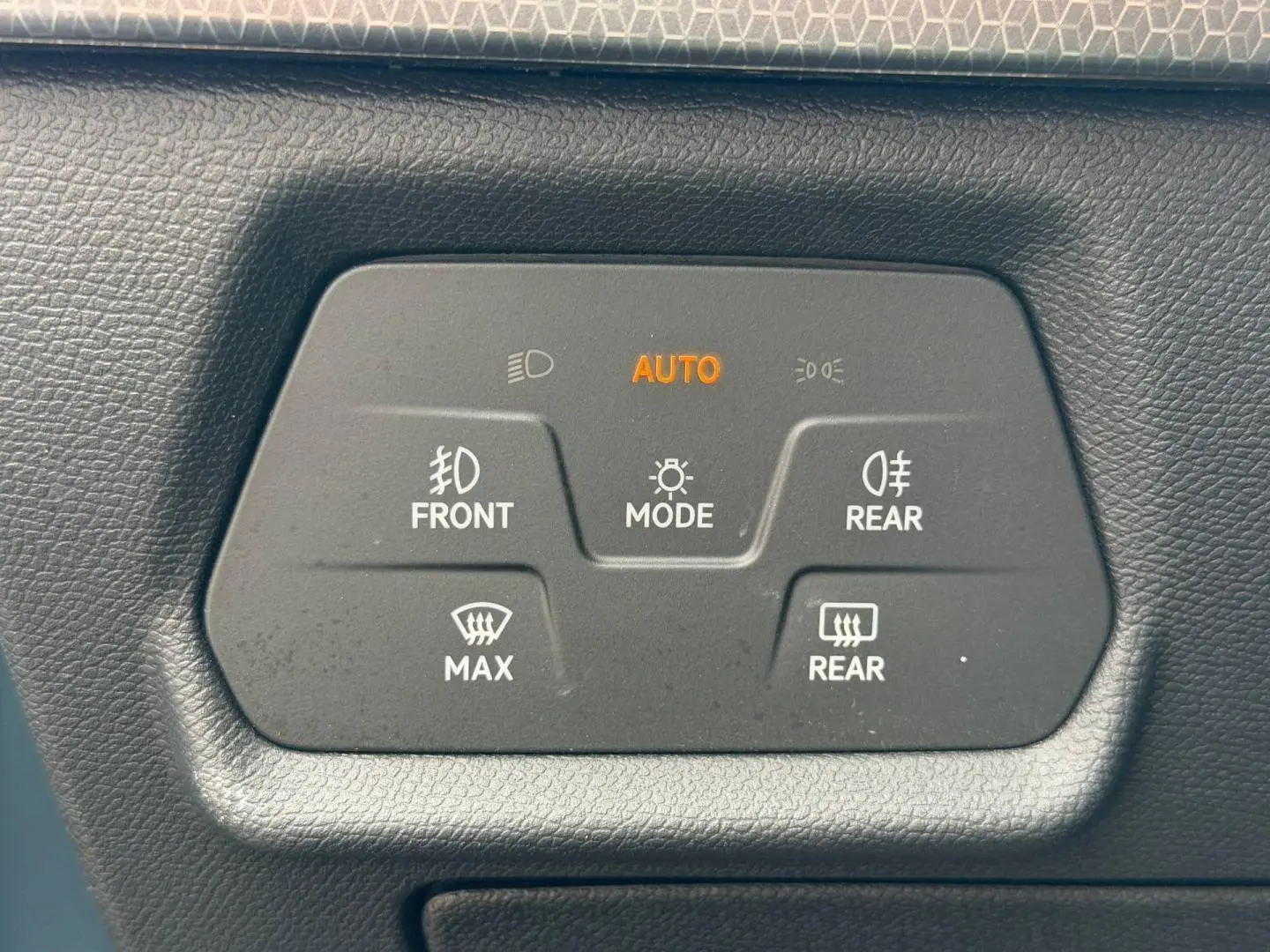 Panneau de commandes d'éclairage et dégivrage avec mode automatique, sur tableau de bord noir d'une SEAT Leon gris magnétique.