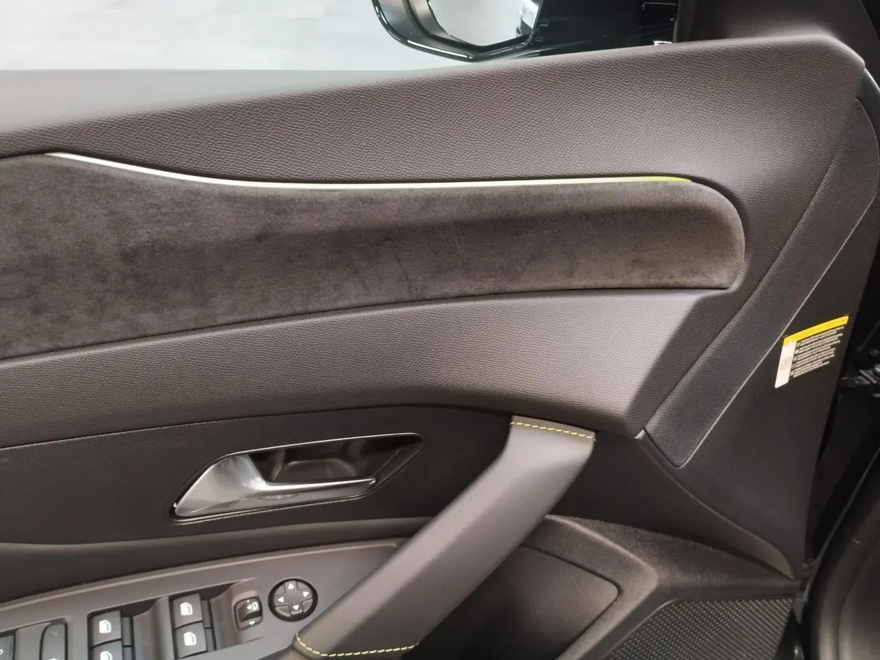Détail de la porte avant gauche de la Peugeot 308 GT 2026, avec surpiqûres vert Adamite et garniture alcantara.