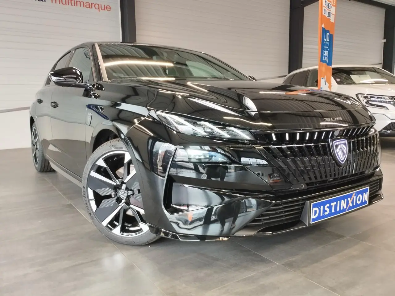 Peugeot 308 noir métallisé vue 3/4 avant gauche avec calandre illuminée et jantes alliage bi-tons.