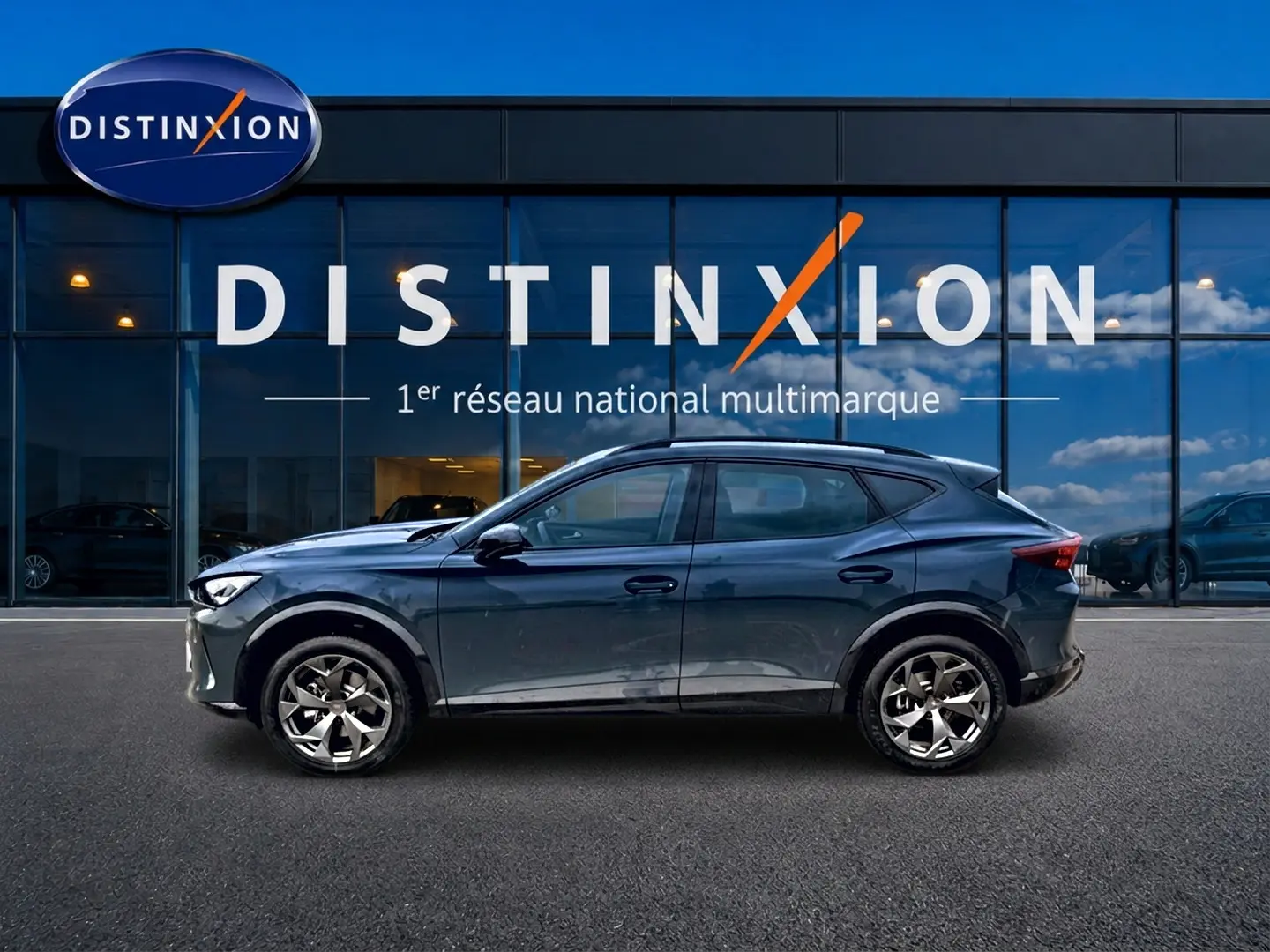 Vue de profil côté gauche d'un CUPRA Formentor 1.5 etsi hybrid bleu fjord devant une vitrine Distinxion.