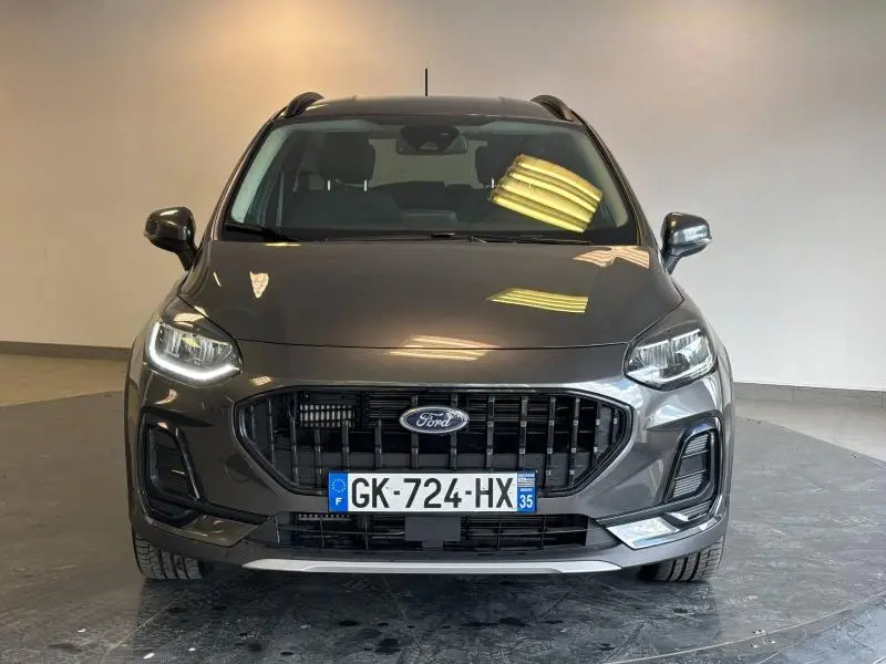 Vue frontale d'une Ford Fiesta 2022 gris Fashion Magnetic avec calandre noire et phares LED allumés.