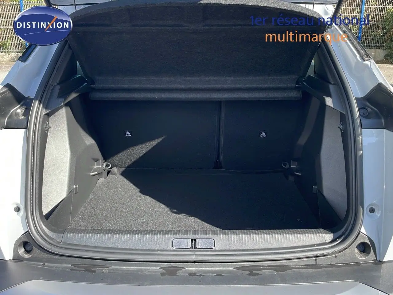 Coffre ouvert vu de l'arrière d'un Peugeot 2008 blanc Okenite Metal, montrant l'espace de chargement vide.