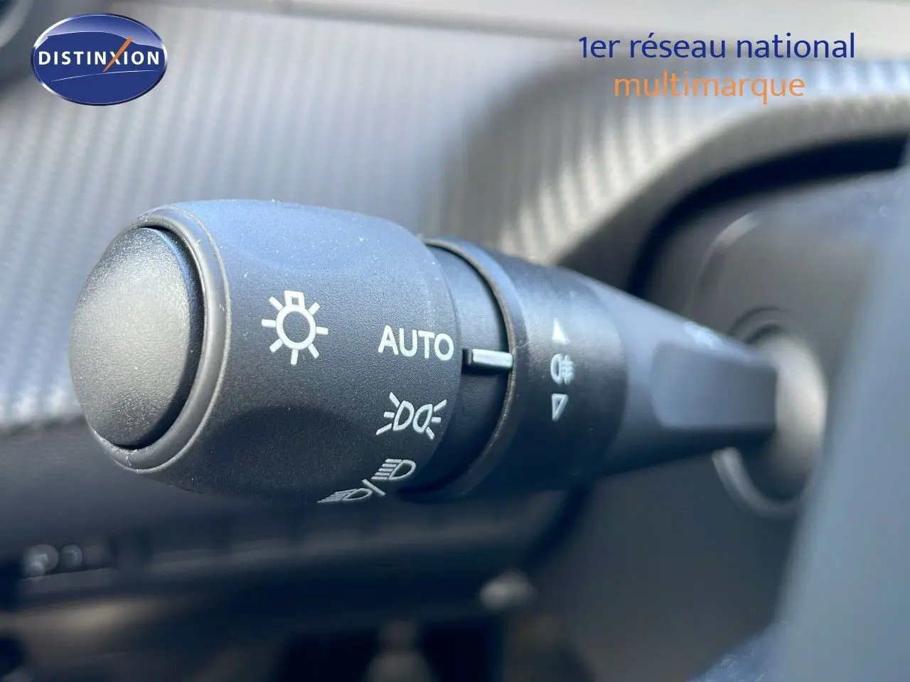 Gros plan sur la commande des phares du Peugeot 2008 blanc Okenite Metal, intérieur avec tableau de bord texturé.