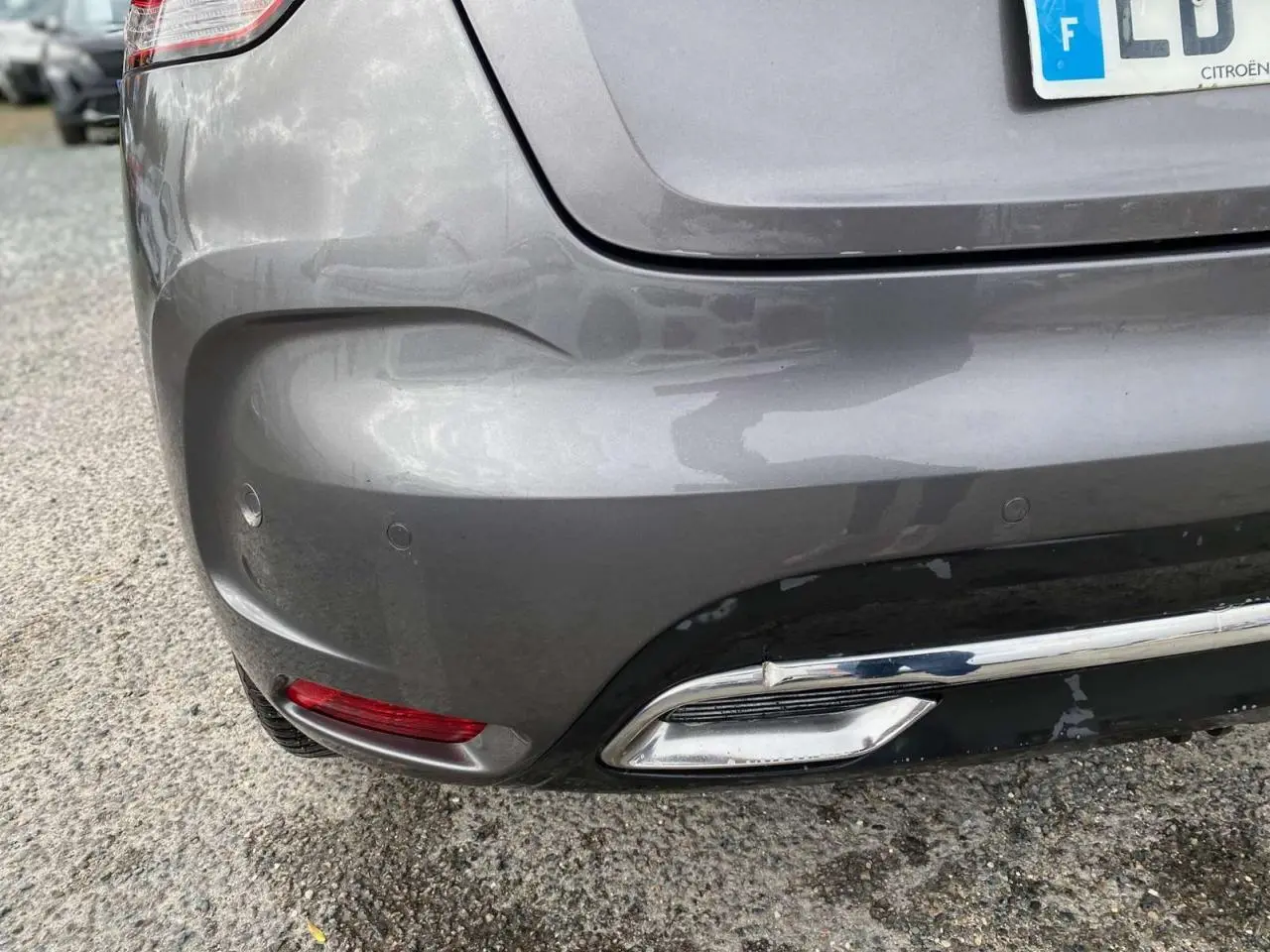 Gros plan sur le bouclier arrière gris clair du DS4 avec feu rouge et embout d'échappement chromé visible.