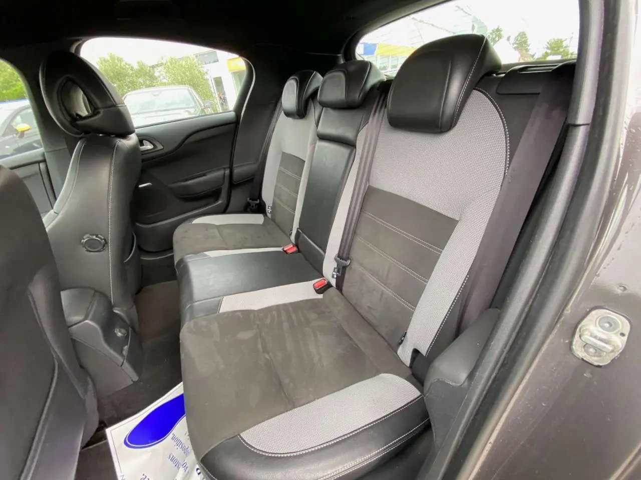 Vue intérieure des sièges arrière bi-matière gris clair et noir d'une DS4 2016, avec ceinture de sécurité et appuie-têtes.