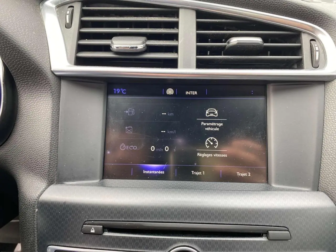 Écran tactile central affichant les réglages de vitesse et paramètres véhicule dans une DS4 gris clair de 2016.