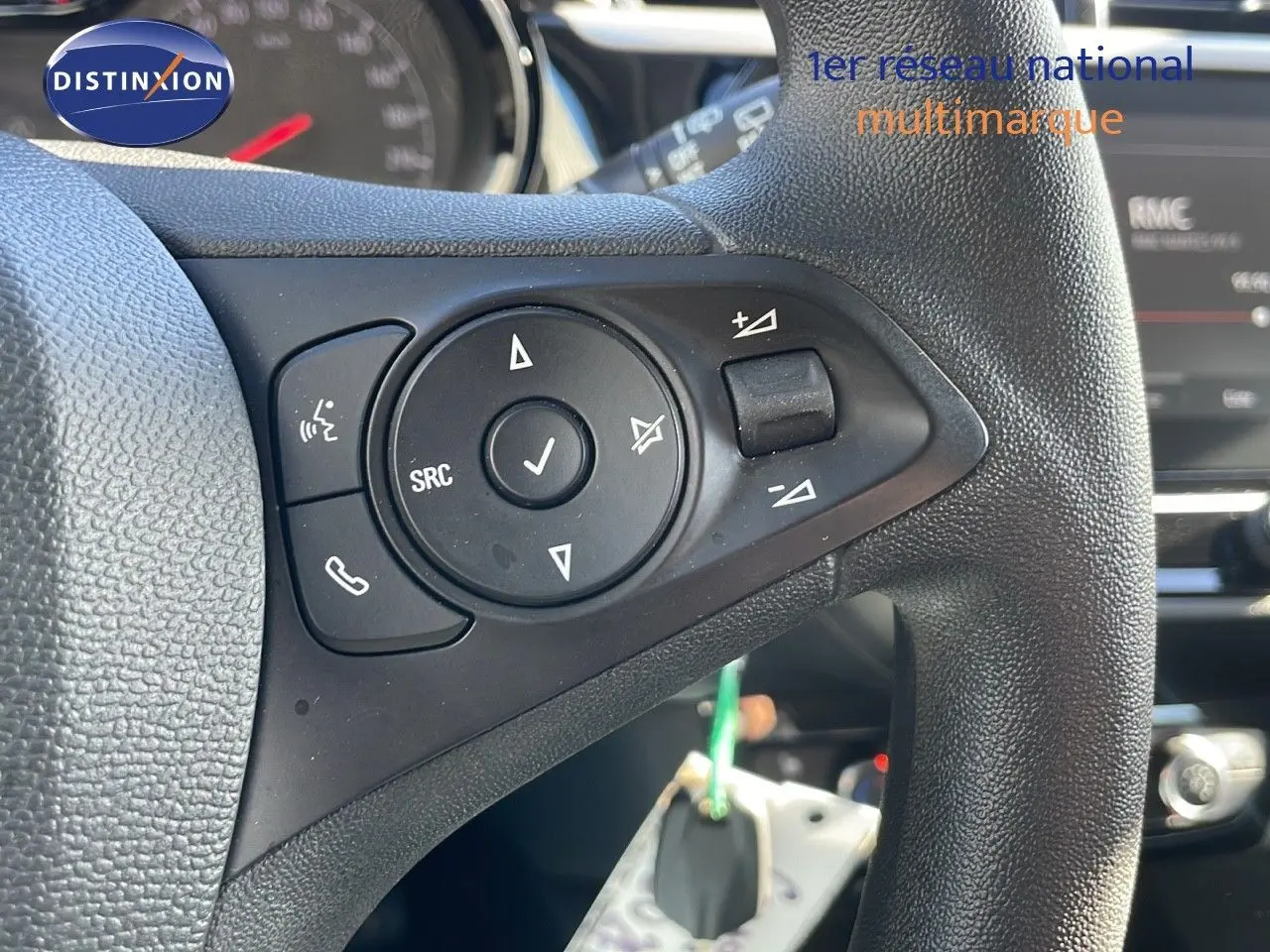 Gros plan sur les commandes au volant noir de l’Opel Corsa blanc glacier 2022, mettant en valeur les boutons multifonctions.