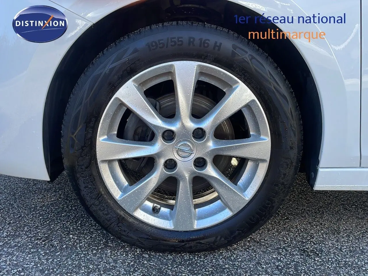Gros plan sur la roue avant gauche d'une Opel Corsa blanc glacier avec jante alliage 16 pouces.